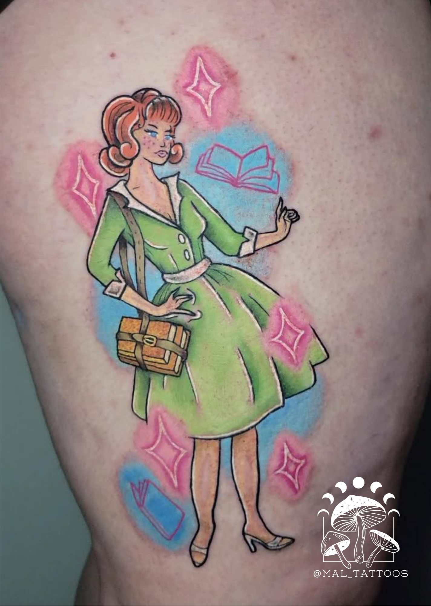 Tattoo of a woman in a green dress with stars and books on a person's arm.